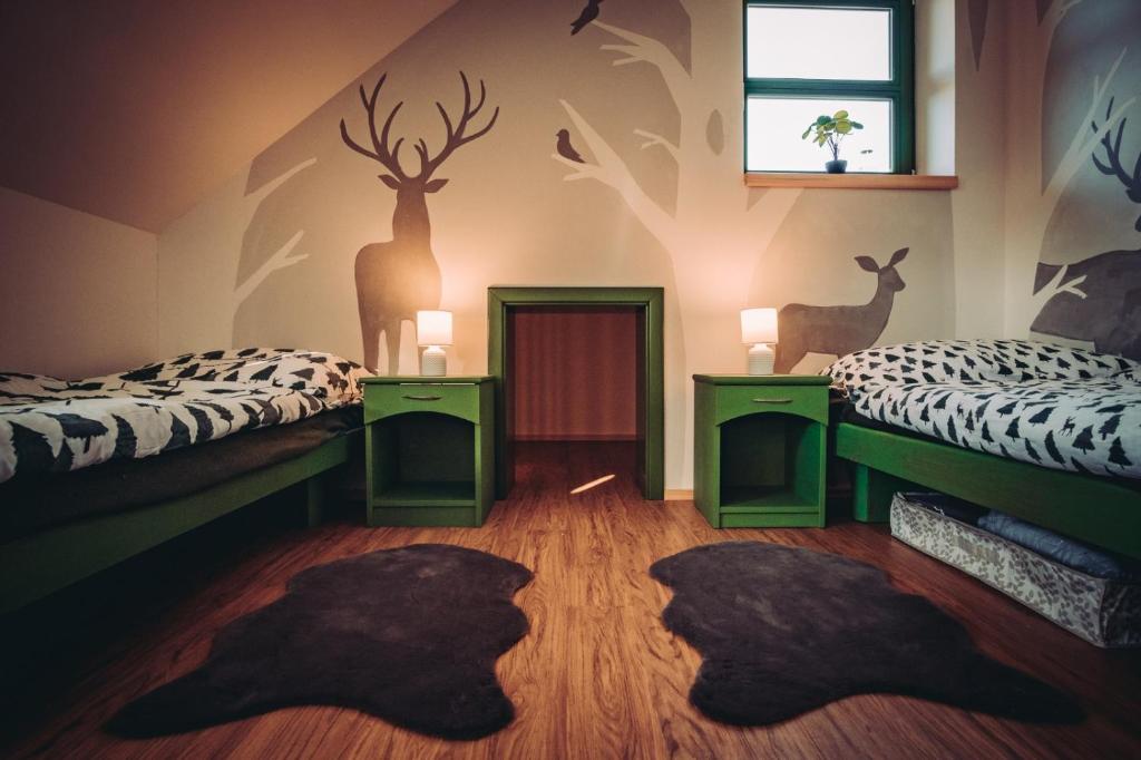 two beds in a room with deer heads on the wall at Zelený Jelen - horský apartmán in Stachy