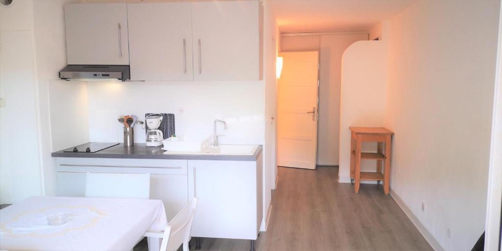 une cuisine avec des armoires blanches et une table dans une pièce dans l'établissement Résidence Cap Azur Appartement 209, à Villeneuve-Loubet