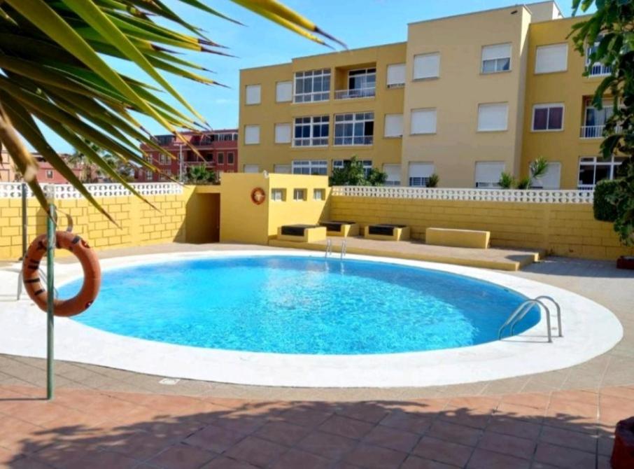 une grande piscine en face d'un bâtiment dans l'établissement El Médano Lagos de Miramar apartamento, à El Médano
