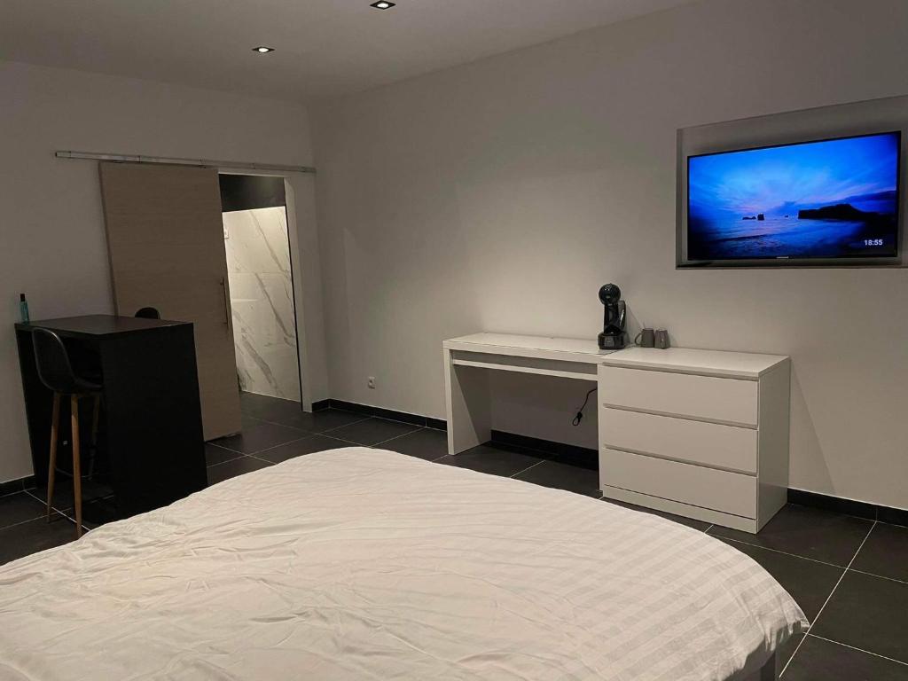 een slaapkamer met een bed en een bureau en een tv aan de muur bij Room of Tournai 2 in Tournai
