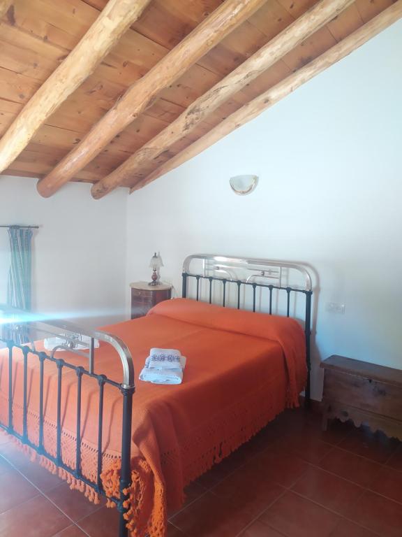 Casa Rural El Cortijo Nuevo, en El Cerezo في El Cerezo: غرفة نوم بسرير ولحاف برتقالي