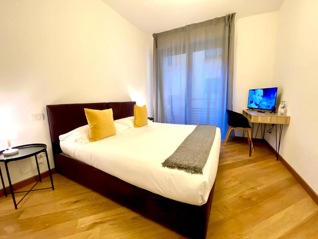 Dormitorio con cama, escritorio y TV en Palazzina B - Smart Rooms, en Génova