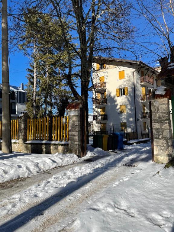 eine schneebedeckte Straße mit einem Zaun und einem Gebäude in der Unterkunft Roccaraso Inn Blu in Roccaraso