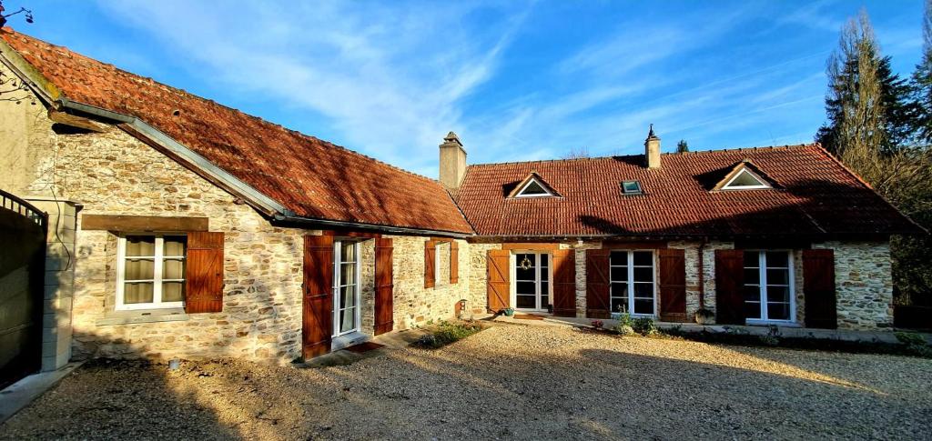 una antigua casa de piedra con techo rojo en Domaine des Pousses, Chambres d'hôtes au coeur d'un village de campagne en Droue-sur-Drouette