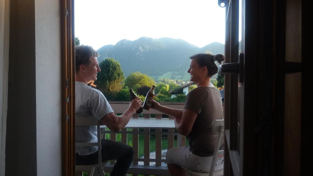 a man and a woman holding up a plant in front of a window at Ferienwohnung mit wundervollen Bergblick in Lenggries