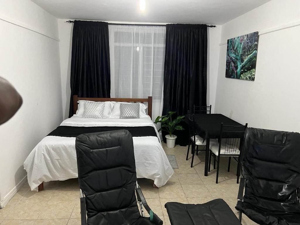 1 dormitorio con 1 cama, mesa y sillas en Johari Shared Studio Westlands, en Nairobi