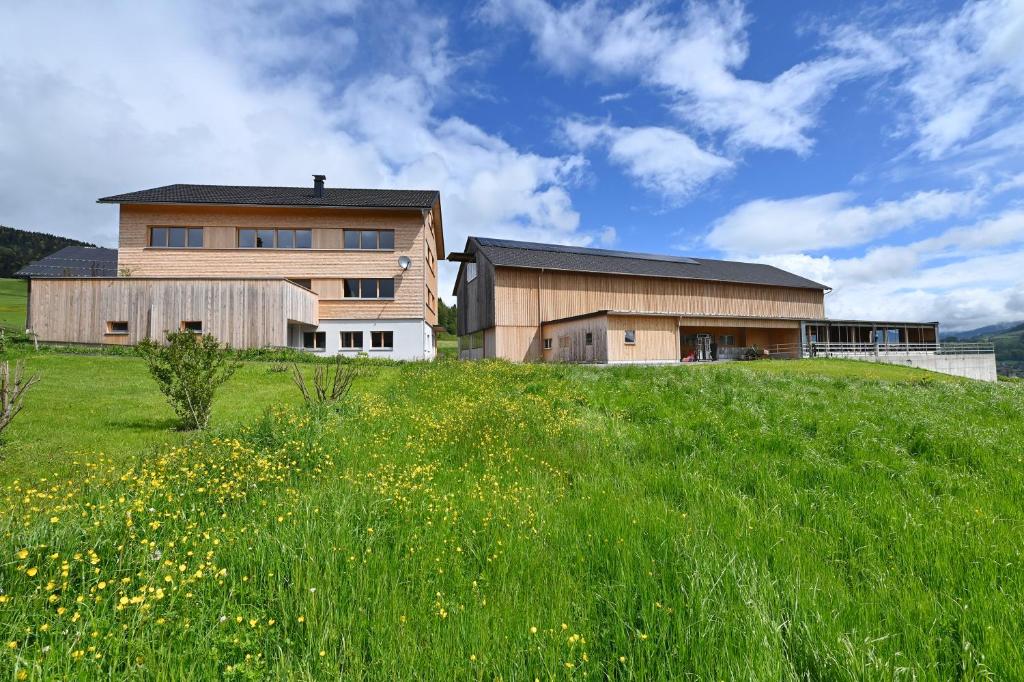 a house on top of a hill with a green field at Ferienhof Landerleben in Egg