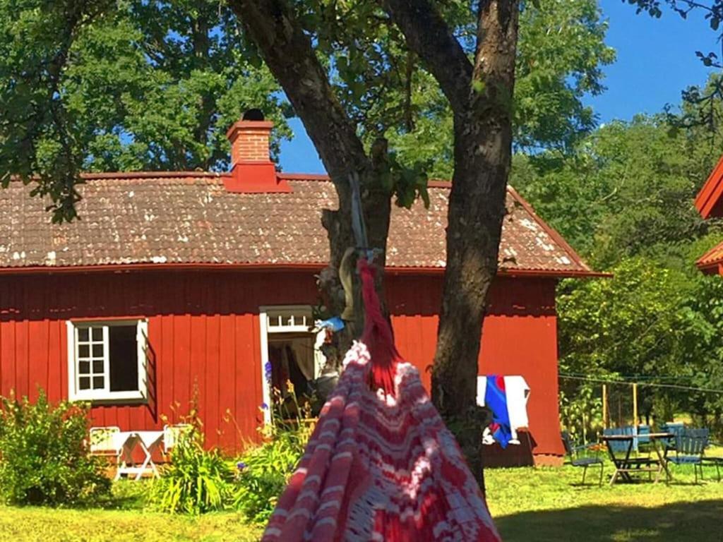 una casa rossa con un albero di fronte di Holiday home HÄLLEKIS a Hällekis