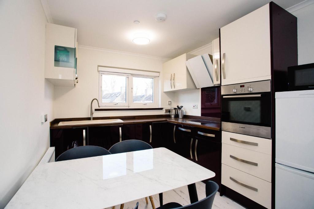 Una cocina con gabinetes blancos y una mesa con sillas. en 2 DoubleBed Rooms Flat in old Aberdeen, near University, en Aberdeen