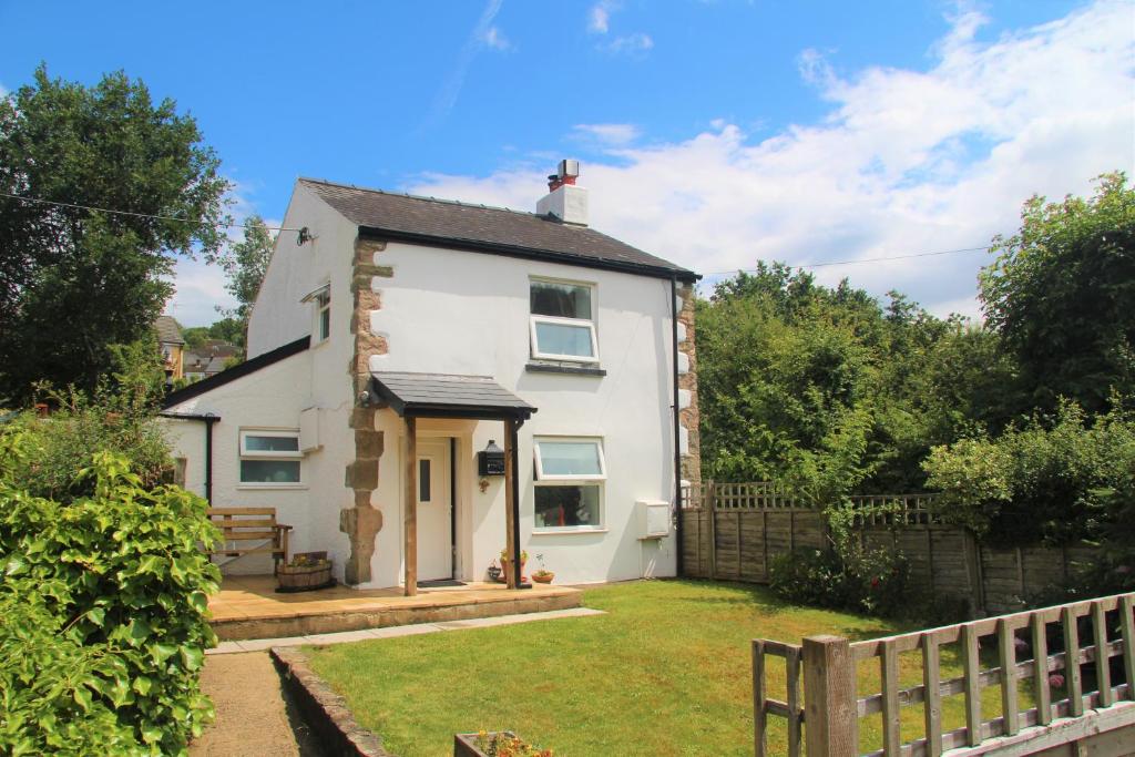 una casa blanca con una valla y un patio en Peacock Cottage, en Cinderford