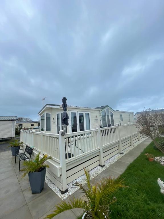 a house with a white fence and a balcony at Luxury Caravan - WI-FI and SMART TV newly installed in Rhyl