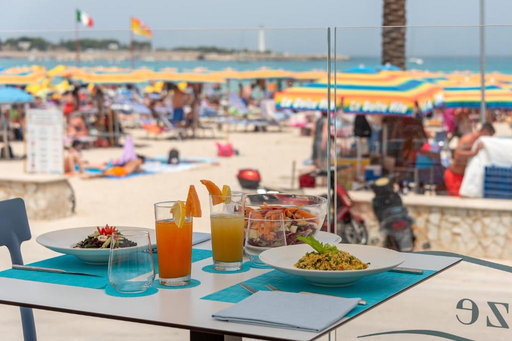 a table with plates of food and drinks on the beach at Hotel Riviera in San Vito lo Capo