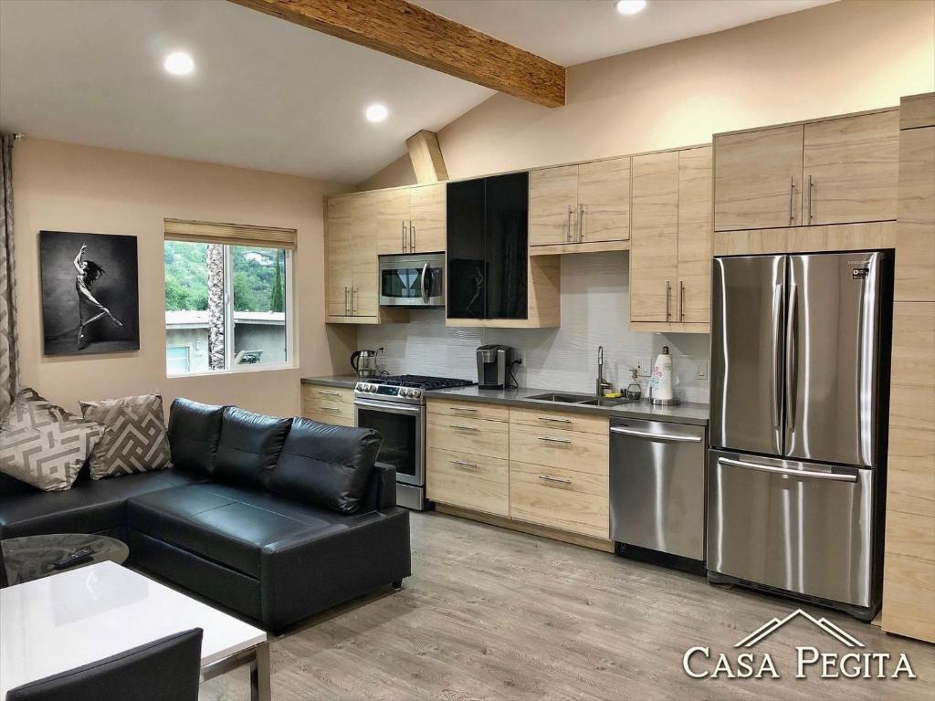 cocina con electrodomésticos de acero inoxidable y sofá de cuero negro en New Contemporary Guest House in Studio City Hills en Los Ángeles