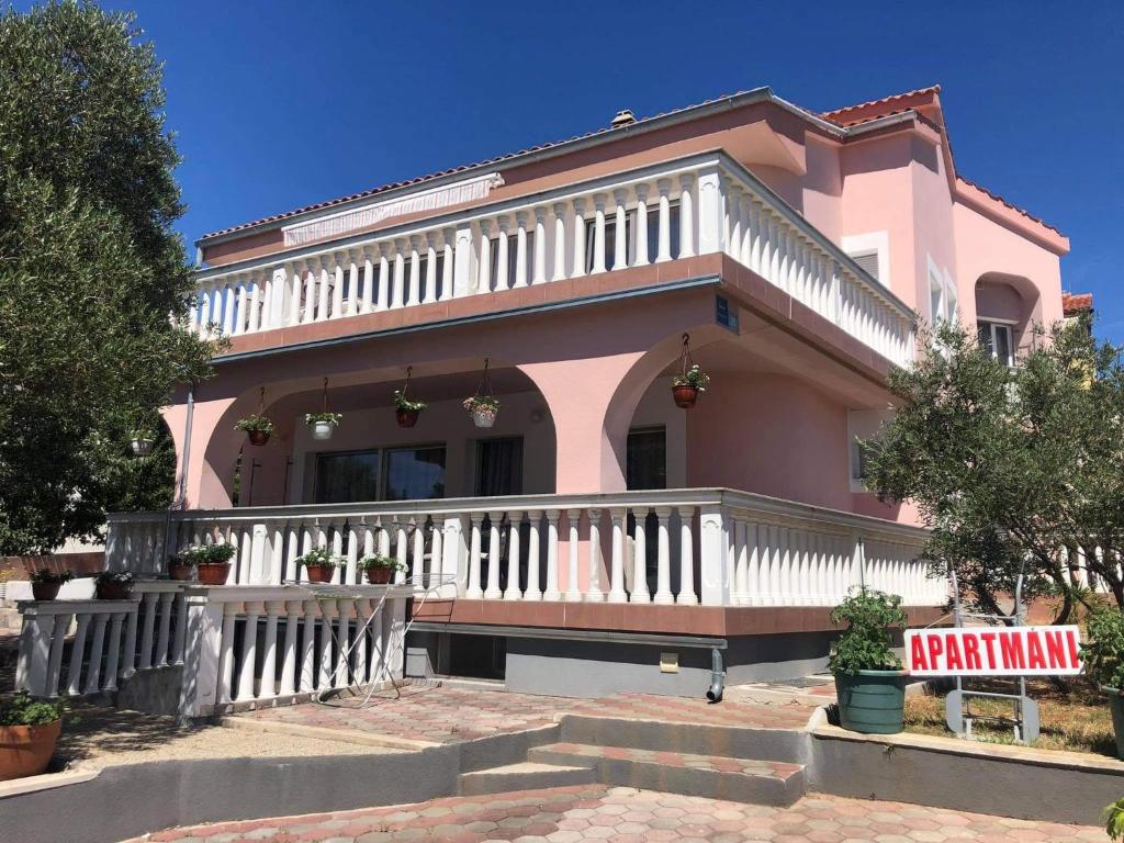 różowy dom z gankiem i znakiem przed nim w obiekcie Krk Kornic Apartments w mieście Kornić