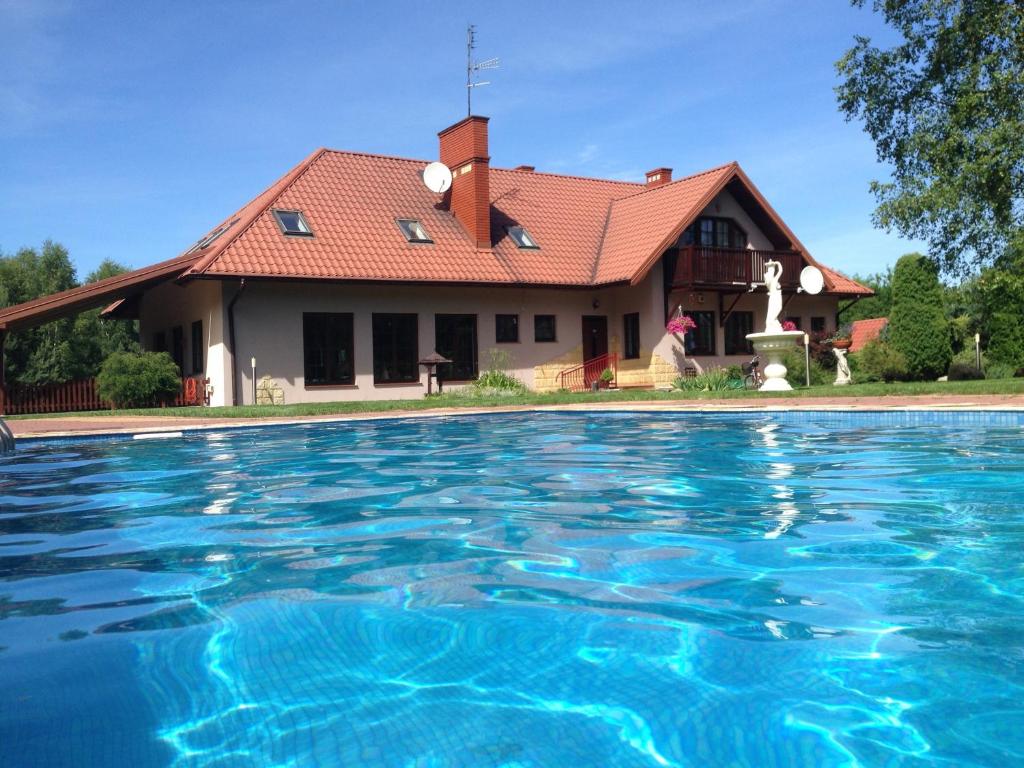 a house with a swimming pool in front of it at Pensjonat u Alexa in Załuski