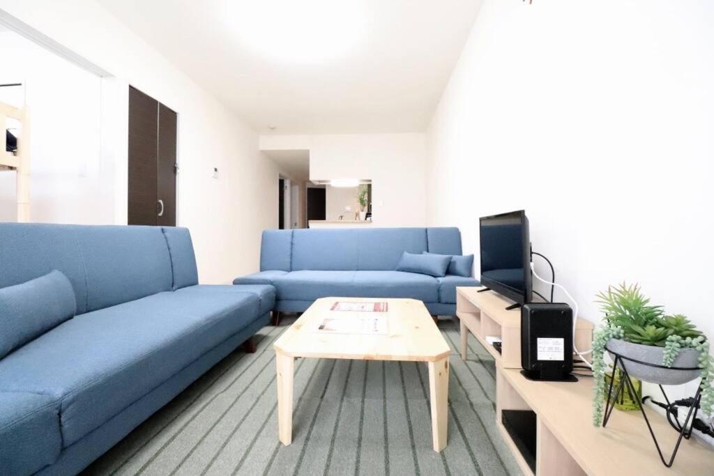 a living room with a blue couch and a table at 札幌市にある１０人宿泊可能物件 in Atsubetsu