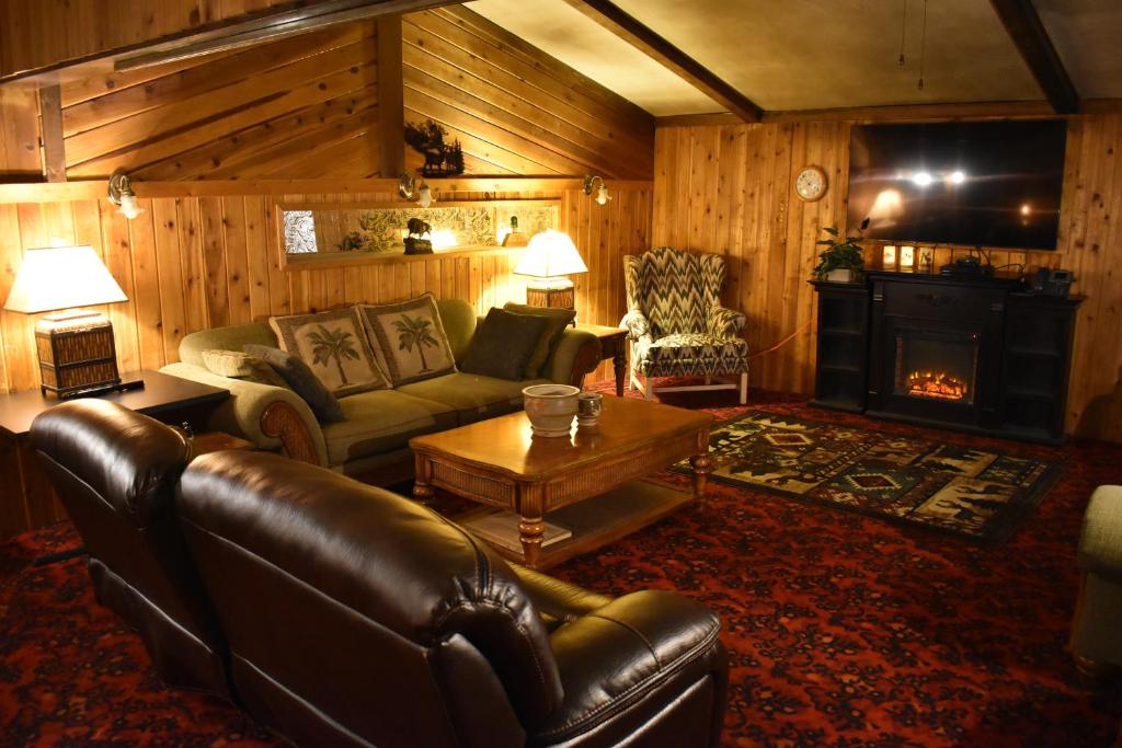 ein Wohnzimmer mit einem Ledersofa und einem Kamin in der Unterkunft Silver Horseshoe Inn in Saint Anthony