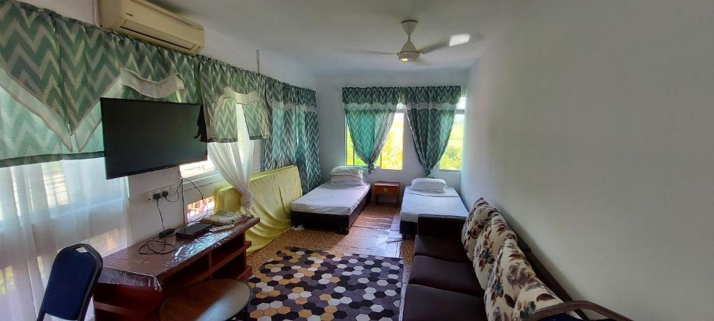 Una sala de estar con un sofá y un televisor. en Pondok Muara Chalet, en Pantai Cenang