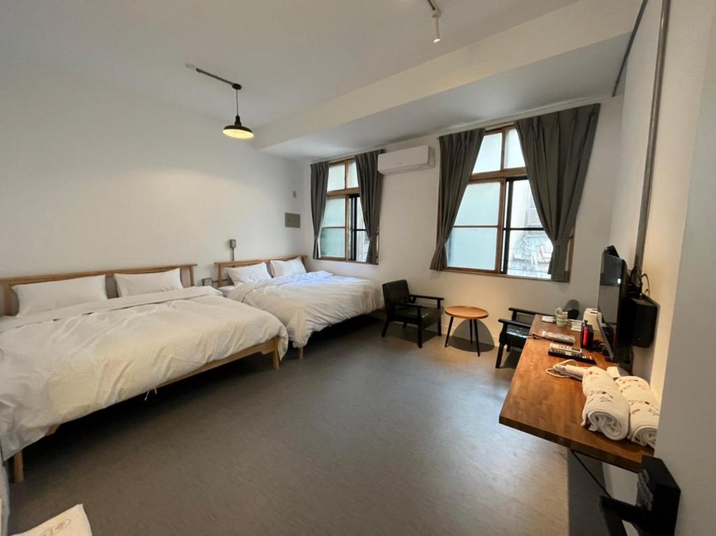 a hotel room with two beds and a table at Rolling Pin Homestay in Tainan