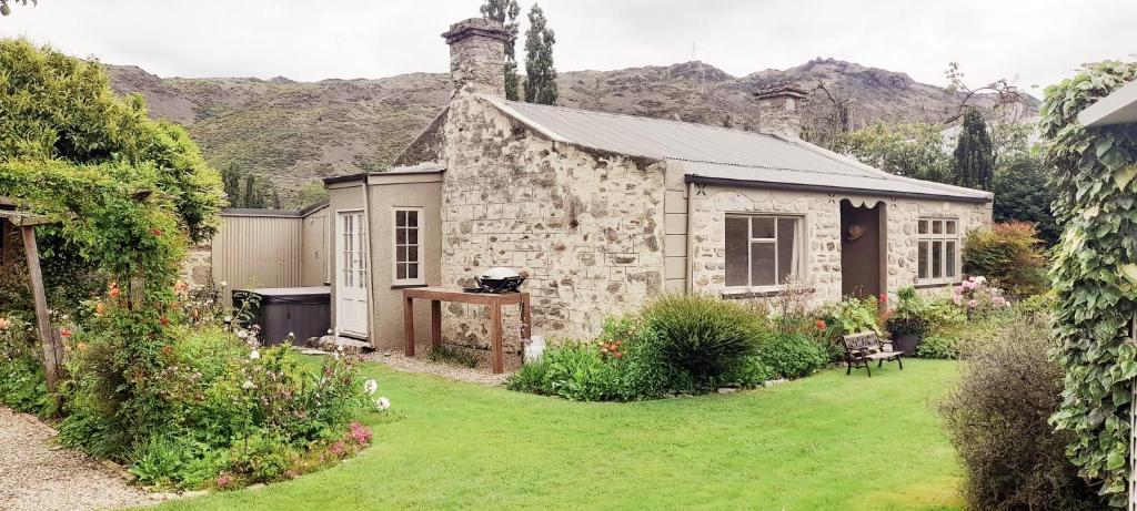 uma antiga casa de pedra num quintal com um jardim em Historic Clyde cottage guest house em Clyde