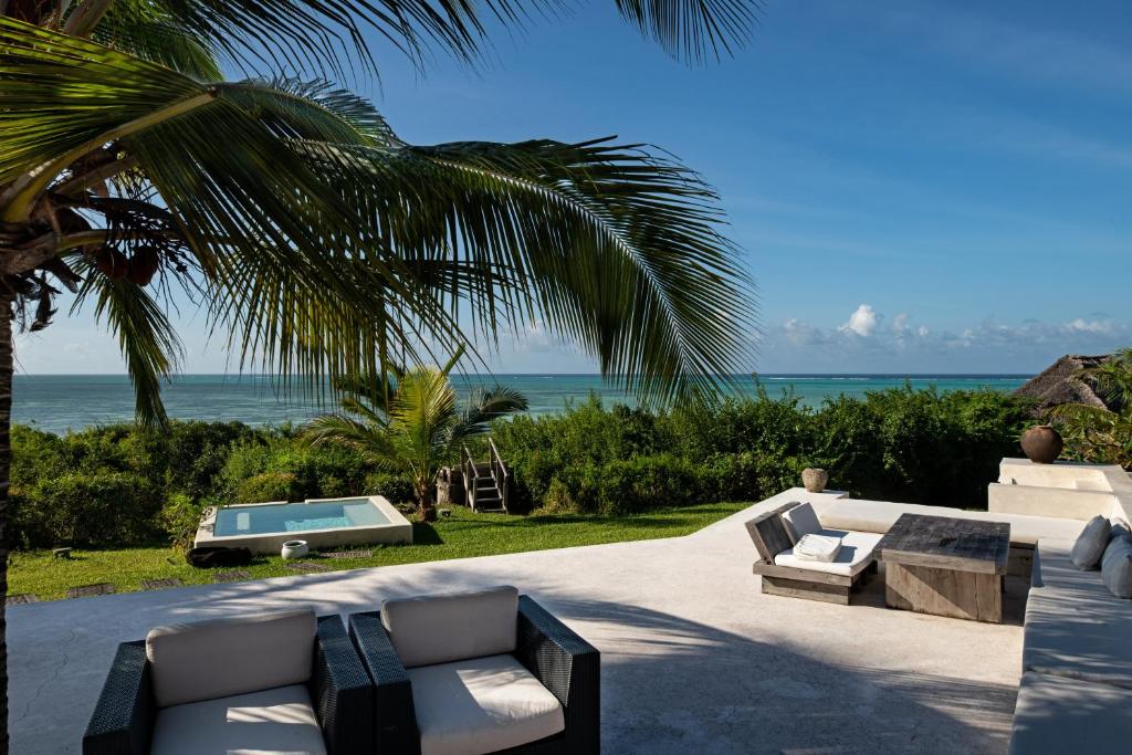 a patio with couches and a swimming pool and the ocean at Qambani Luxury Resort in Michamvi