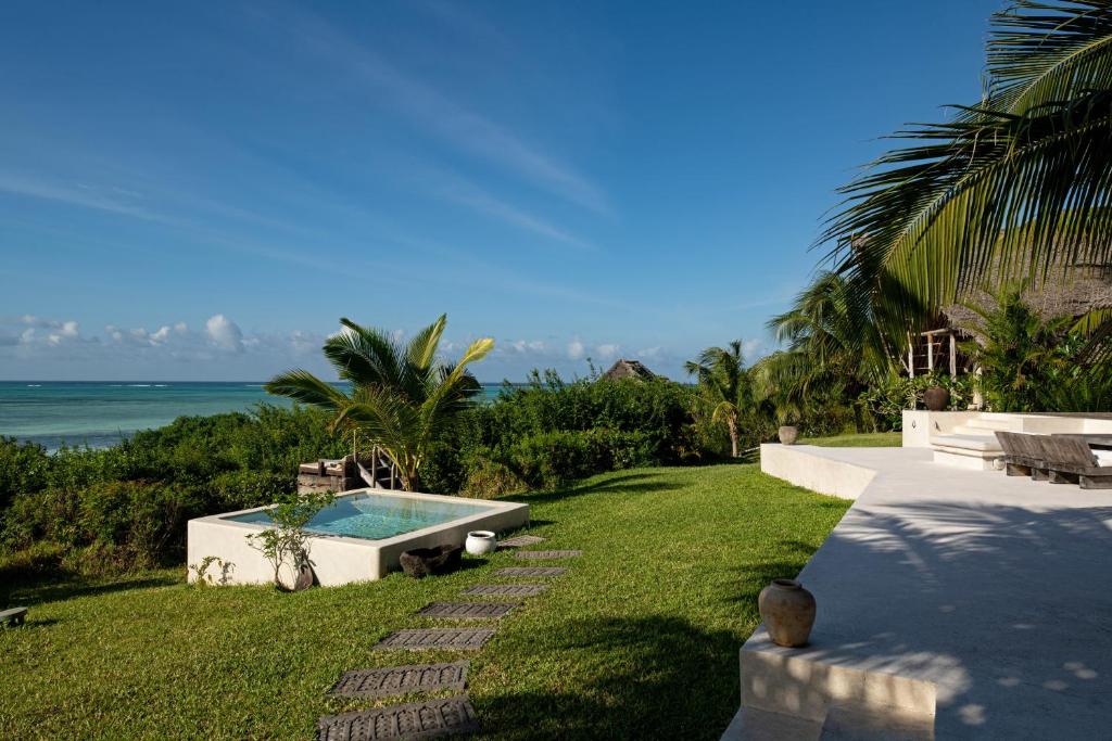 a backyard with a swimming pool and the ocean at Qambani Luxury Resort in Michamvi