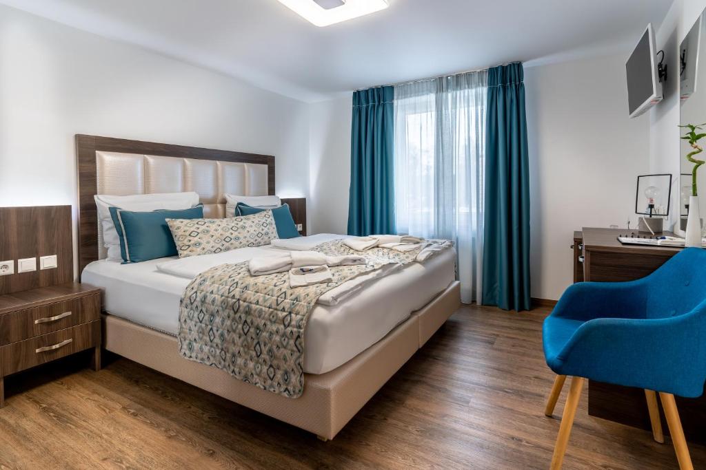 Hotel Myrsini في Kirchentellinsfurt: غرفة نوم بسرير وكرسي ازرق