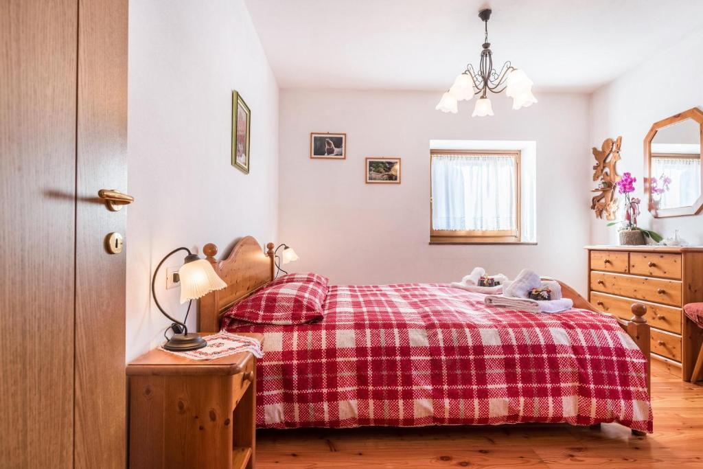 a bedroom with a bed with a red plaid blanket at Agritur Alle Quattro Stagioni in Tonadico