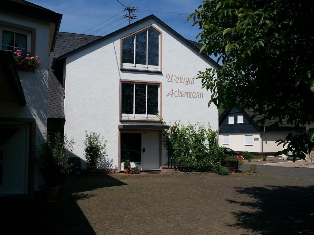 ein weißes Haus mit einem Schild an der Seite in der Unterkunft Ferienwohnung Weingut Ackermann in Zeltingen-Rachtig