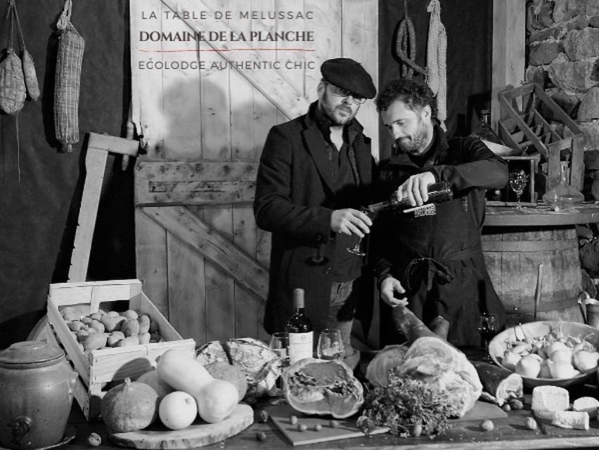 twee mannen naast een tafel met eten bij Domaine de la Planche de Melussac in Cussac-sur-Loire