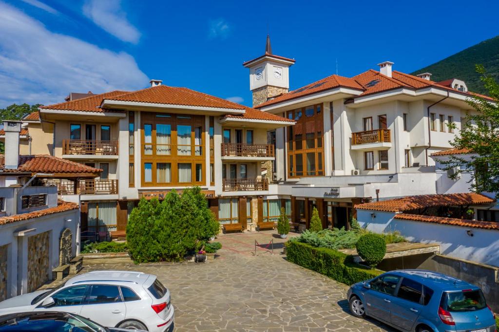 un edificio con coches estacionados en un estacionamiento en National Palace Spa & Wellness Hotel en Sliven