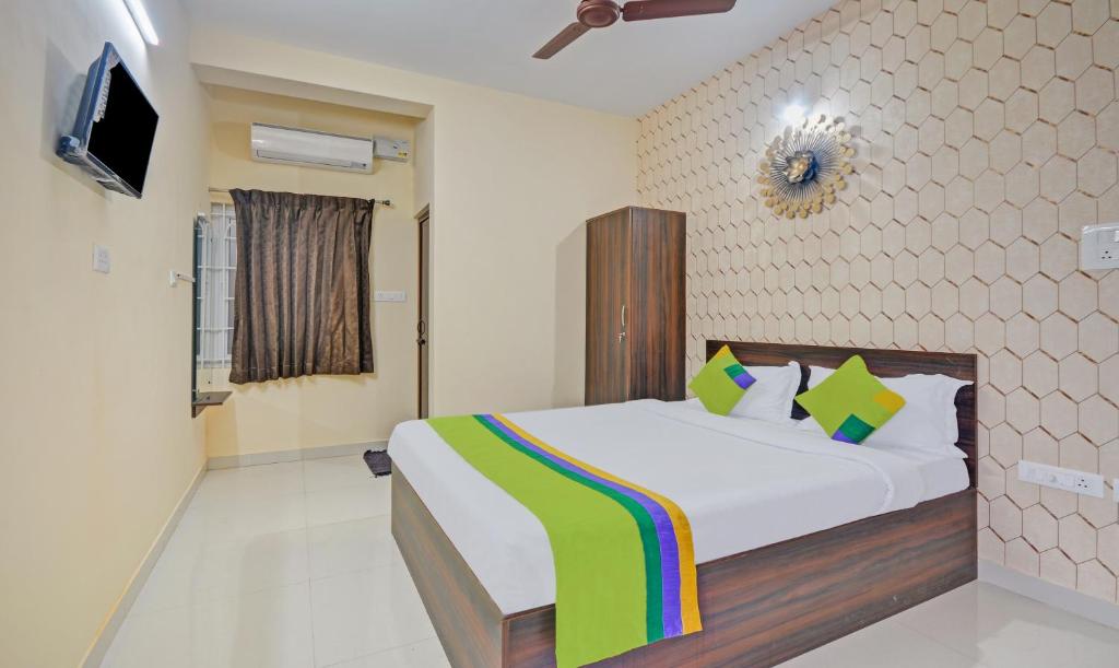a bedroom with a bed and a tv on a wall at Treebo Trend Everest Residency Tidel Park in Coimbatore