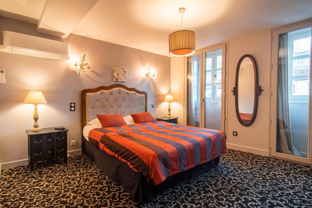 a bedroom with a large bed and a mirror at Hôtel Itzalpea in Saint-Jean-Pied-de-Port