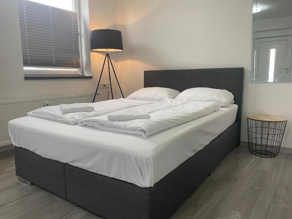 1 cama grande con sábanas blancas y almohadas. en Urbanes, modernes Apartment mit Parkplatz, en Kassel