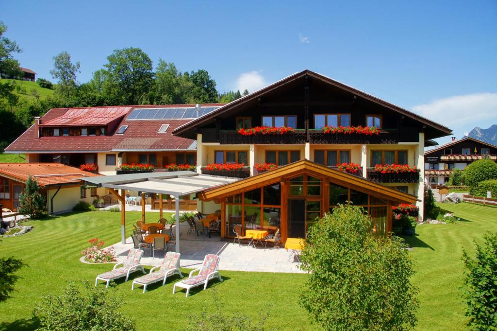 ein großes Haus mit Stühlen davor in der Unterkunft Hotel Landhaus Schmid in Fischen im Allgäu