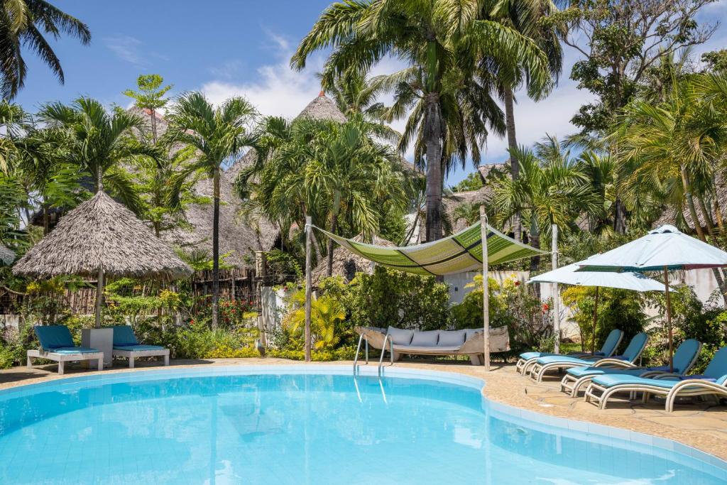 una piscina in un resort con sedie e ombrelloni di Aestus Villas Resort a Diani Beach