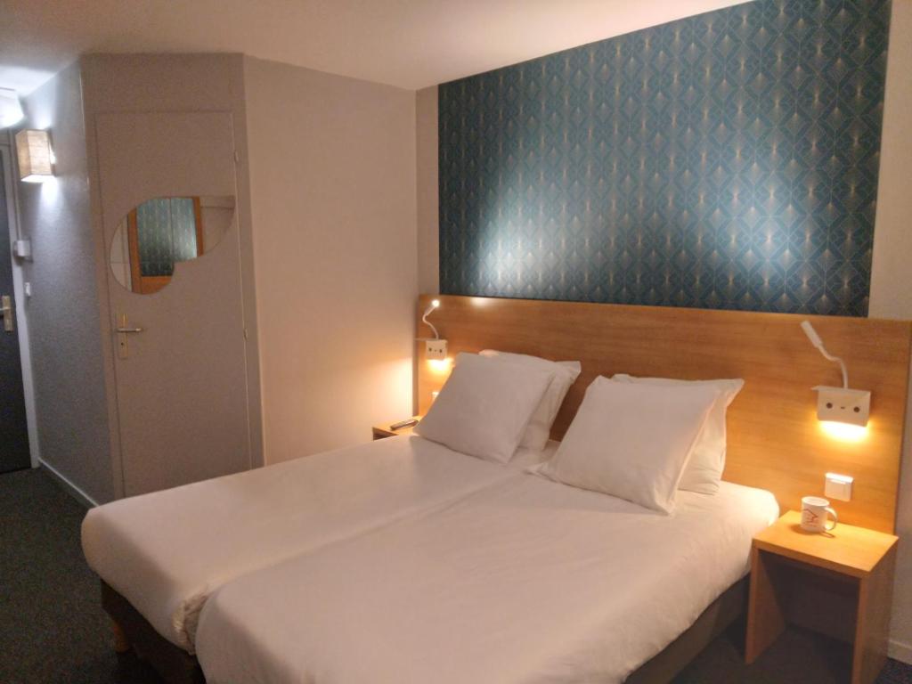a bedroom with a large white bed and a blue wall at Cit&#39;Hotel Hotel Prime - A709 in Saint-Jean-de-Védas