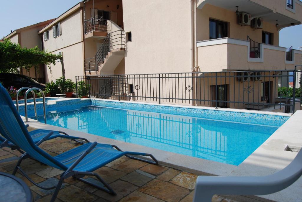 una piscina con 2 sillas y un edificio en Apartments Srzentic, en Petrovac na Moru