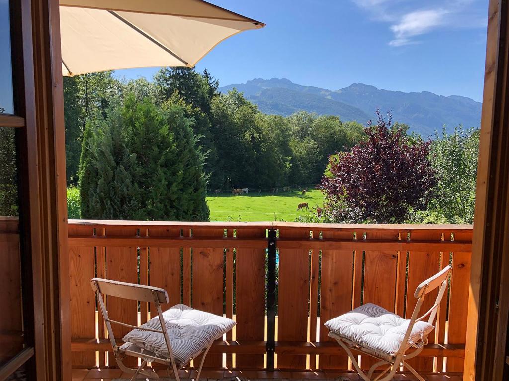 2 Stühle auf einer Veranda mit Blick auf ein Feld in der Unterkunft Ferienwohnung Florina in Frasdorf