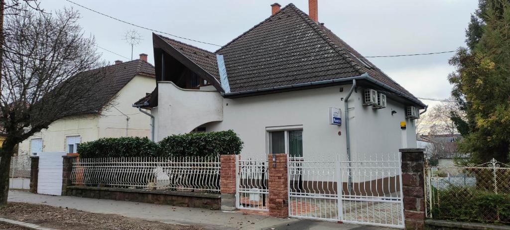 uma casa branca com uma cerca à frente. em Éva Vendégház em Kaposvár