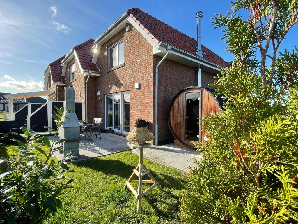 a brick house with a garden and a lamp in the yard at Meerwunder in Wangerland