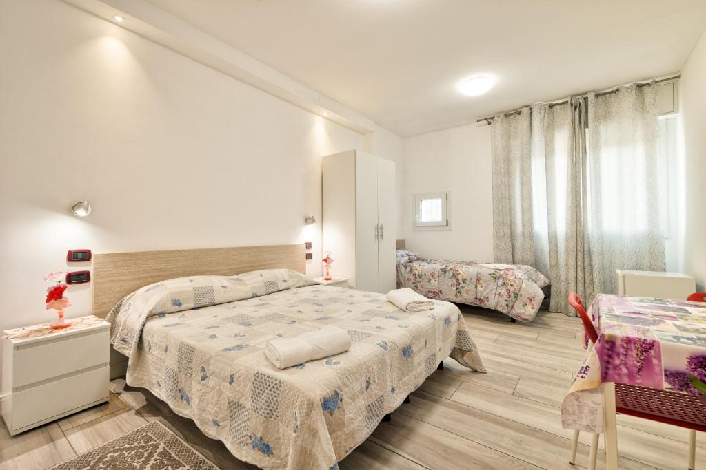 a white bedroom with two beds and a table at Venice Pink House in Marghera