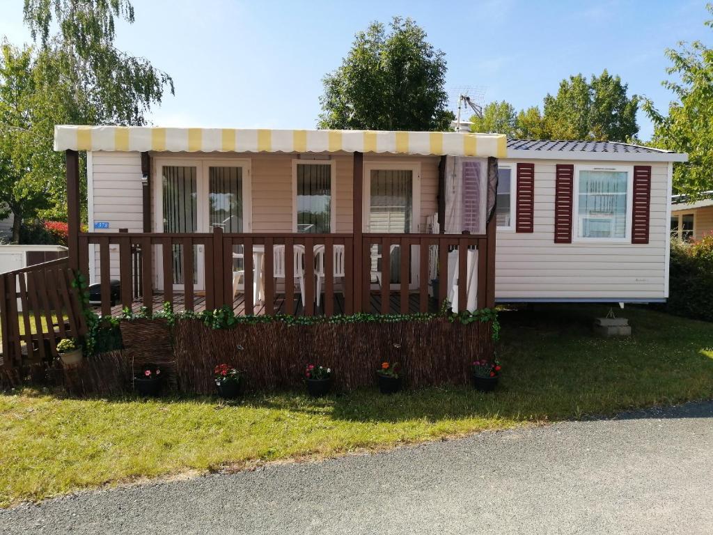 una casa pequeña con porche y valla en Bungalow cosy à Onzain avec terrasse & piscine partagée, en Onzain