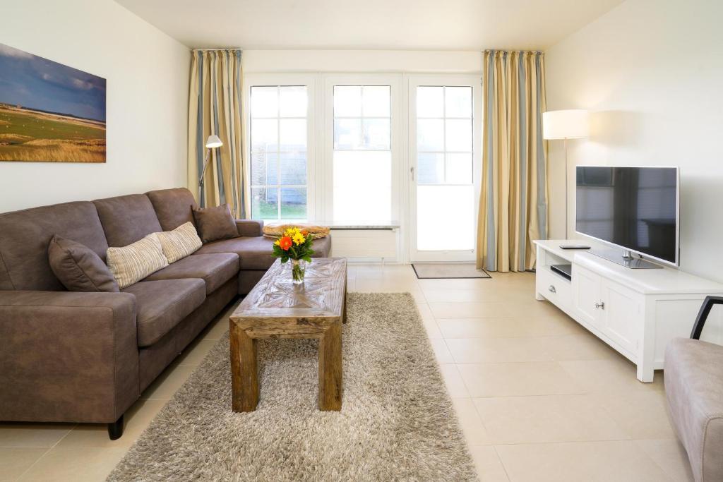 ein Wohnzimmer mit einem Sofa und einem TV in der Unterkunft Strandhaus WHG NR 1 "Meer Strand Und Design in Wenningstedt" in Wenningstedt-Braderup