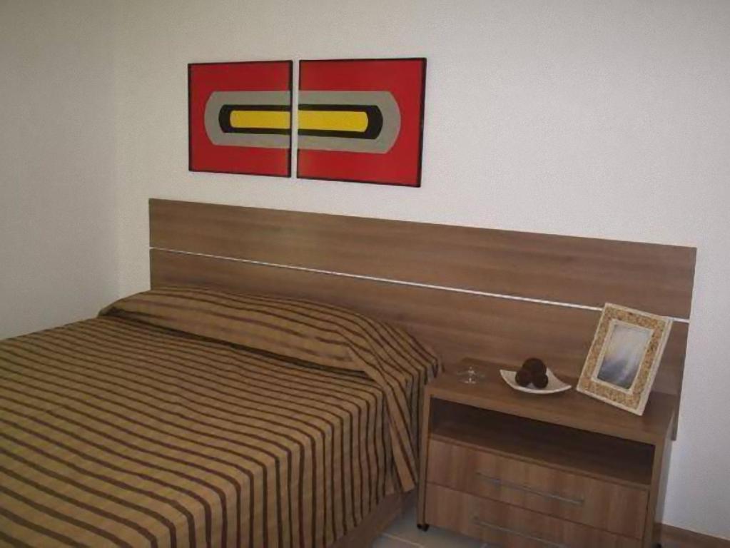 ブラジリアにあるBiarritz Hplus Long Stayのベッドルーム1室(ベッド1台付)が備わります。壁に絵が飾られています。