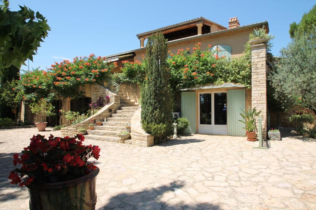 a house with a bunch of flowers in front of it at Villa Thebaïde Chambres d'hôtes in Laudun