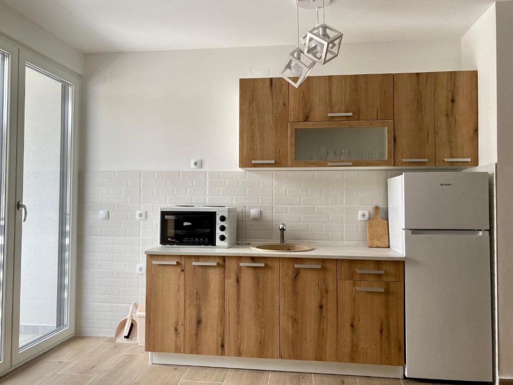 - une cuisine avec des placards en bois et un réfrigérateur blanc dans l'établissement Apartman Anastasija Jezero, à Divčibare