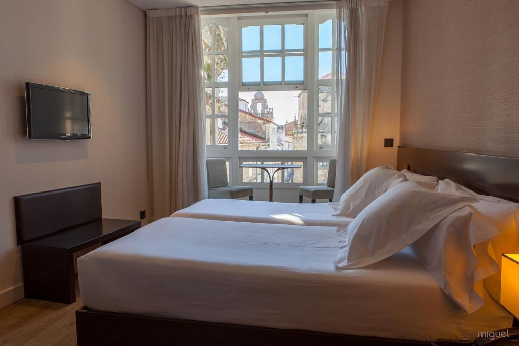 a hotel room with two beds and a window at Hotel San Miguel in Santiago de Compostela