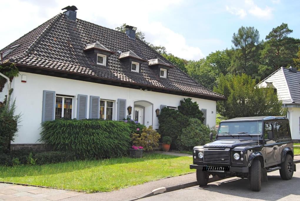 ein schwarzer Jeep, der vor einem weißen Haus parkt in der Unterkunft Exklusive Villa am Wald mit Garten, Waldzugang und Sauna in Solingen