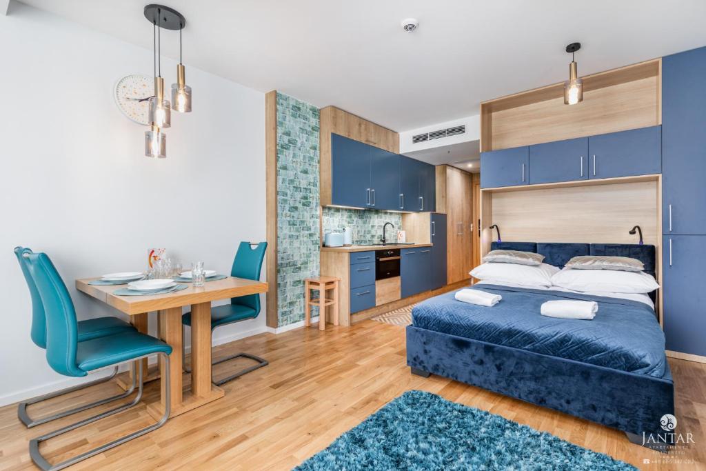 a bedroom with a bed and a desk and a table at Jantar Apartamenty - SeaView SEASIDE in Kołobrzeg